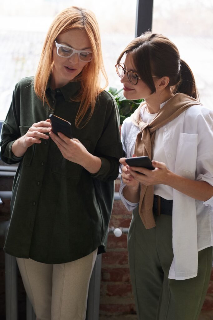 Two women talking through social media management, looking at eachother's phones.